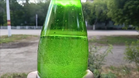 Hands open a bottle of sparkling water on the street. Gas bubbles in the water. Stock Footage 311697285