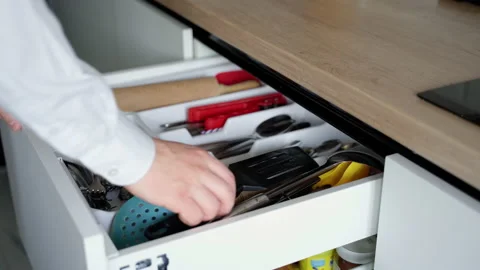 Hands open a drawer with kitchen utensils and puts a frying spatula Stock Footage 153289801