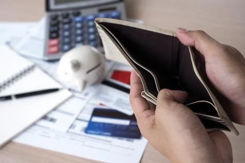 Hands open the empty purse after calculating the cost from the credit card an Stock Photos