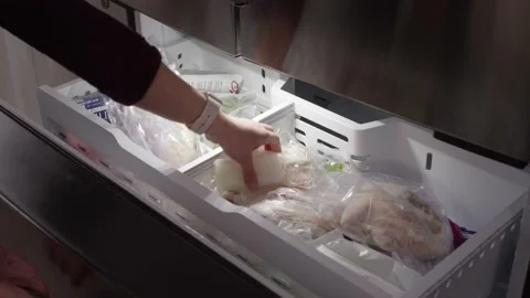 Hands open freezer and start taking out food to prepare to defrost the freezer Stock Footage 147613422