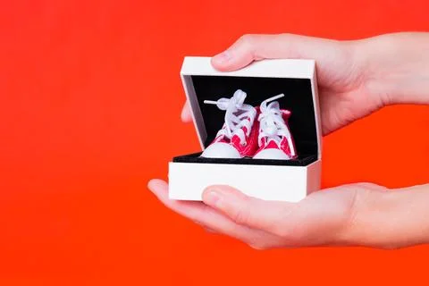 Hands Open a Gift Box with Tiny Red Canvas Shoes 스톡 사진