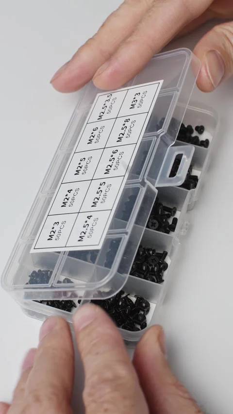 Hands open a labeled organizer of M2 screws for electronics, computer repair and Stock Footage 346874928