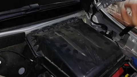 Hands open or install a dusty black plastic cover under the hood of a car. Stock Footage 343420068
