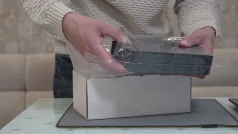 Hands open the shipping box and take out a new black external hard drive Stock Footage 344687802