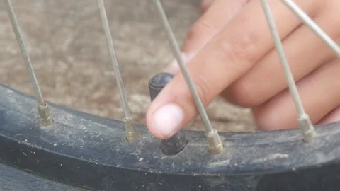 Hands opening and closing the valve of a bicycle tire Stock Footage 332866883