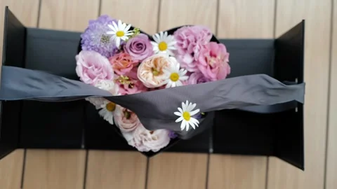 Hands opening a black gift box to reveal a heart-shaped floral arrangement Stock Footage 328230391