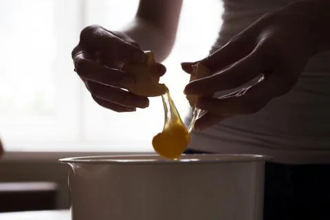 Hands opening broken eggshell of brown raw egg Stock Photos