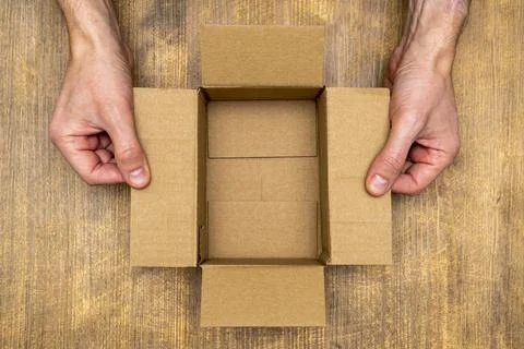 Hands opening empty brown cardboard box Stock Photos
