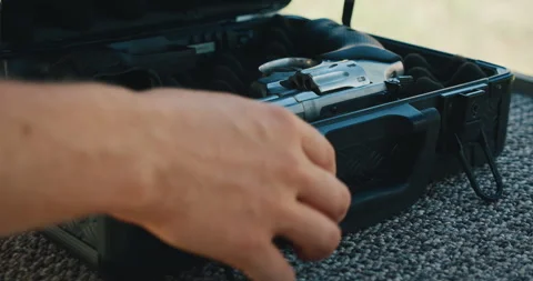 Hands opening gun case with revolver resting inside on foam outdoors Stock Footage 311489258