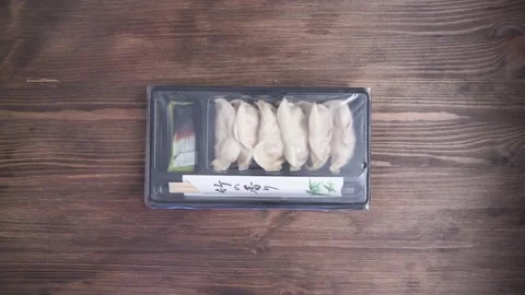 Hands opening plastic tray with precooked gyozas Stock-Footage 136410213