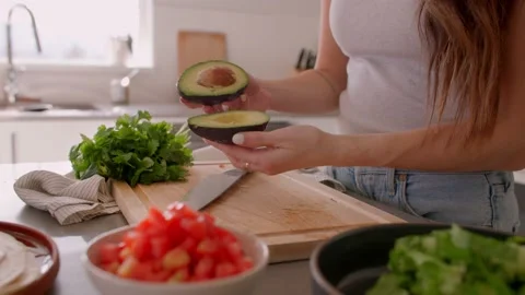 Hands opening up ripe avocado in kitchen, cooking Stock Footage 220754483
