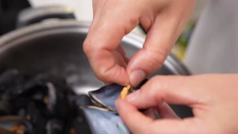 Hands opening a steamed mussel shell to eat the tender meat inside Видео 346799766