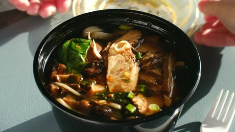 Hands opening a takeout container of ramen noodle soup for lunch Video stock 337548911