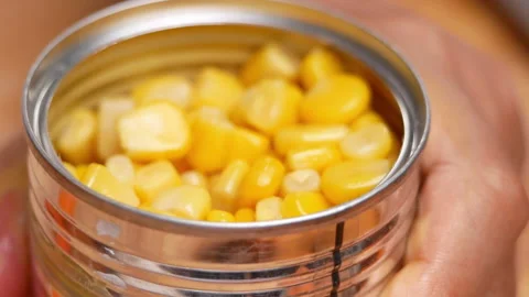 Hands opening tin can with corn kernels, close-up. Corns canned goods 動画素材 158658244