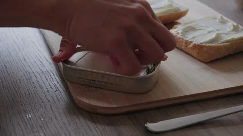 Hands Opening a Tin Can of Sardines on Cutting Board Stock Footage 345834743