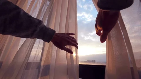 Hands opening white curtains to see sunset city view Video stock 332275680