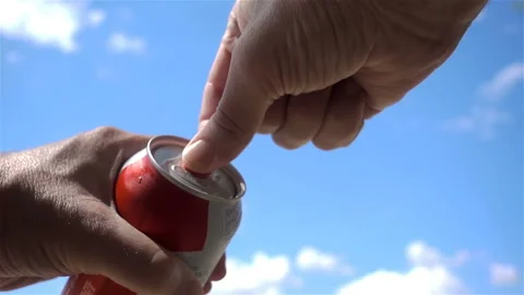 Hands opens a can of beer in slow motion against a blue sky Stock Footage 137027225