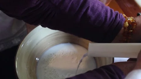 Hands operate a vintage cream separator, processing fresh milk in a rustic Stock Footage 319980344