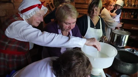 Hands operate a vintage cream separator, processing fresh milk in a rustic Stock Footage 320073877