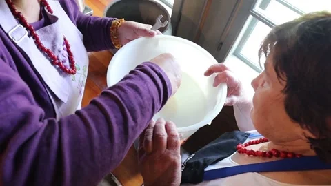 Hands operate a vintage cream separator, processing fresh milk in a rustic Stock Footage 320074232