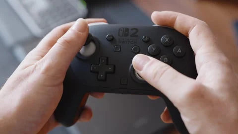 Hands Operating Black Game Controller Indoors Beside Laptop Computer Stock Footage 345691242