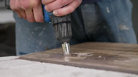 Hands operating blue power drill with hole saw bit cutting wooden board in Stock Footage 344876724