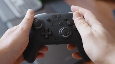 Hands Operating Game Controller Indoors Near Laptop on Desk in Montrichard Stock Footage 345692404