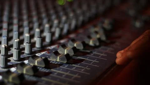 Hands operating knobs of light and sound board console at a concert theater Stock Photos