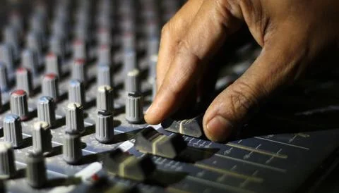 Hands operating knobs of light and sound board console at a concert theater Stock Photos