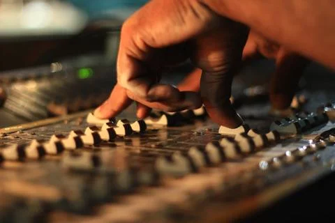 Hands operating slider of light and sound board console at a concert theater Stock Photos