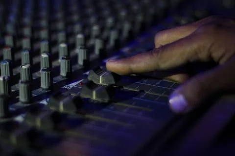 Hands operating slider of light and sound board console at a concert theater Stock Photos