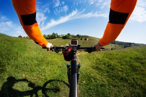 Hands in orange jacket holding handlebar of a bicycle Stock Photos