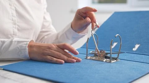 Hands Organizing Documents in Blue Office Binder Foto stock