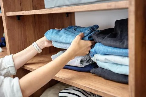 Hands organizing folded clothes in wardrobe Stockfoto's