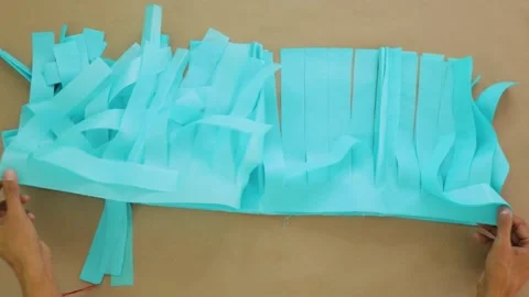 Hands organizing strips of light blue tissue paper for DIY project on flat Stock Footage 284318053