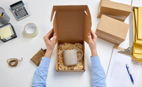 Hands packing mug to parcel box at post office Foto stock