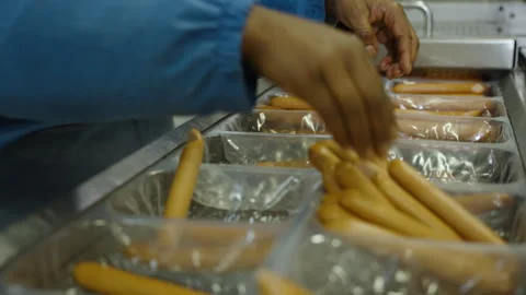 Hands Packing Sausages Into Plastic Trays on Processing Line Stock Footage 340295385