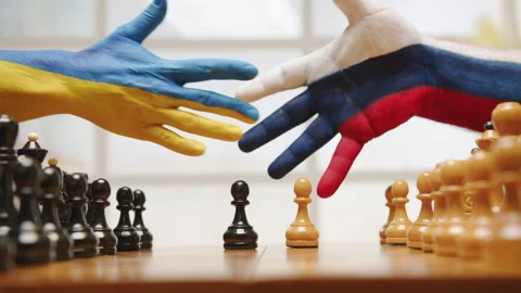 Hands painted in flags of Ukraine and Russia reach out hesitantly for handshake Stock Footage 245064623