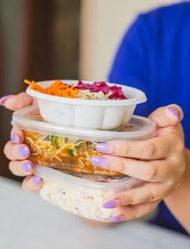 Hands with painted nails hold three stacked containers filled with vibrant Stock Photos