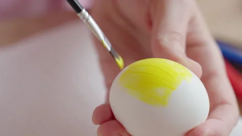 Hands painting Easter egg with yellow paint Stock Footage 328049755