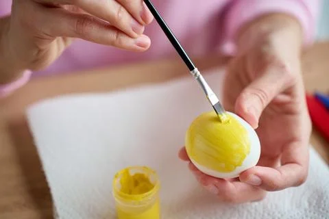 Hands painting Easter egg with yellow paint Stock Photos