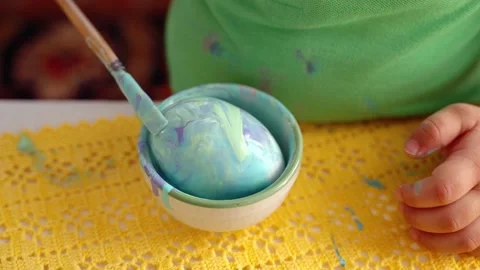 Hands painting Easter eggs with paint and brush by a child Stock Footage 177939715