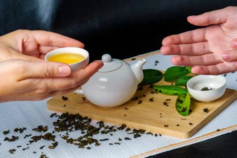 Hands pass each other a small bowl of green tea Stock Photos