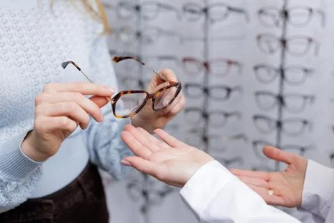 Hands passing eyeglass frames during optician consultation in optical store.. Stock Photos