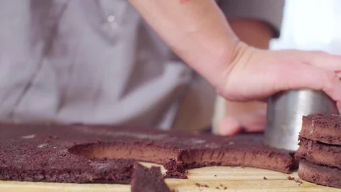 Hands of the pastry chef cutting out round cakes from chocolate dough Video stock 98094316