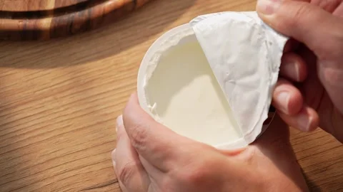 Hands peel back lid from white yogurt container on wooden table Stock Footage 312708281