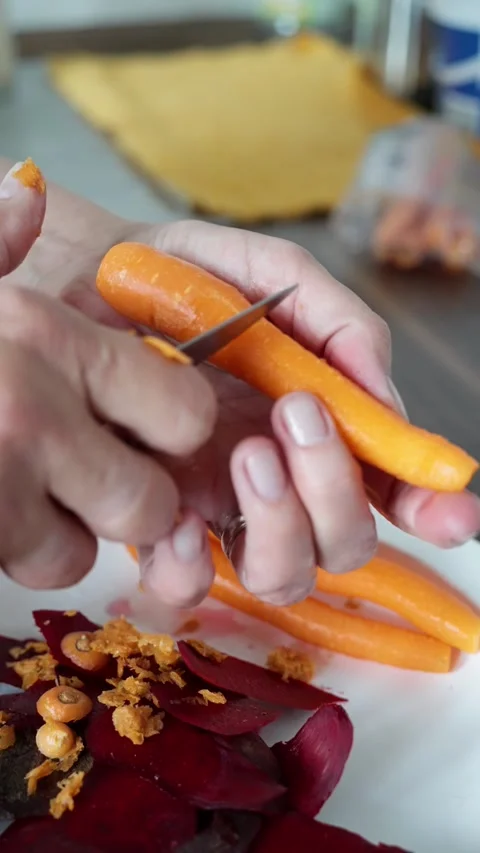 Hands peel carrot, preparing vibrant healthy salad, handful of ingredients Stock Footage 319442217