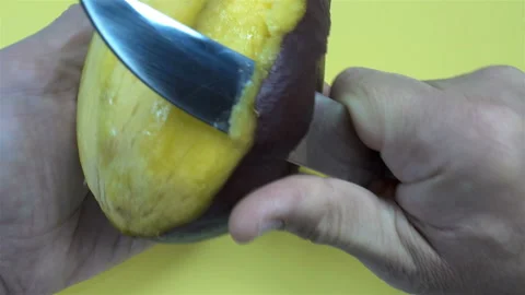 Hands peel the skin of a mango fruit in 4K Video stock 143151341