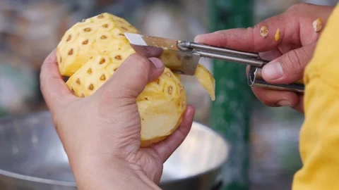 Hands peeling and trimming a pineapple with a knife at a market stall. Tropical Vídeos de archivo 342140054