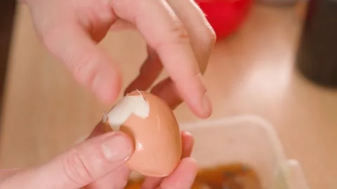 Hands peeling a boiled chicken egg from the shell, close-up, top view Stock Footage 324701525